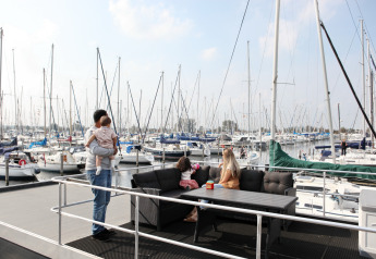 Familia disfruta en la houseboat 4-Almere en Marina Parcs Almere, Países Bajos, rodeados de veleros en el puerto.