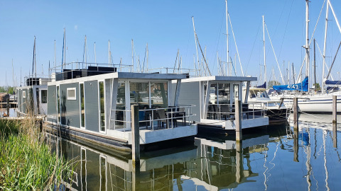 Zwei moderne Hausboote am Marina Parcs Almere, vertäut im Wasser mit Segelbooten in den Niederlanden.