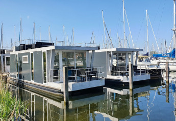 Due moderni houseboat alla Marina Parcs Almere ormeggiati in acqua, con barche a vela nei Paesi Bassi.