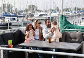 Famiglia rilassata su una houseboat a Marina Parcs Almere, Paesi Bassi, circondata da barche a vela.