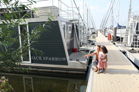 Das Hausboot Jack Sparrow liegt im Jachthafen Marina Parcs Almere in den Niederlanden, mit zwei Mädchen am Steg.