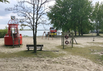 Parco giochi su spiaggia sabbiosa con boa rossa, alberi e lago vicino a House boat 4-Almere, Paesi Bassi.