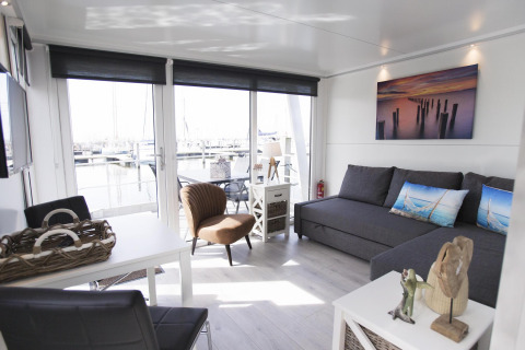 Sala de estar elegante en la House boat 4-Almere en Marina Parcs Almere, Países Bajos, con vista al puerto deportivo.