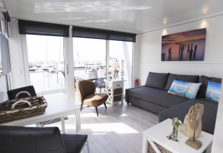 Sala de estar elegante en la House boat 4-Almere en Marina Parcs Almere, Países Bajos, con vista al puerto deportivo.
