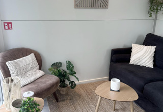 Hyggelig stue på en husbåd i Almere med moderne møbler, grønne planter og neutrale farver.
