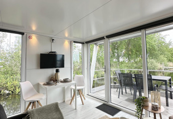 Interno luminoso di houseboat con grandi finestre e terrazza, presso Marina Parcs Almere nei Paesi Bassi.