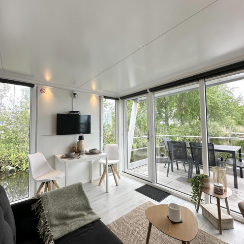Intérieur lumineux d’un houseboat avec grandes fenêtres et terrasse, à Marina Parcs Almere aux Pays-Bas.
