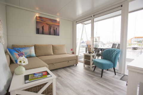 Interieur van House boat 4-Almere bij Marina Parcs Almere in Nederland, met bank en grote ramen.