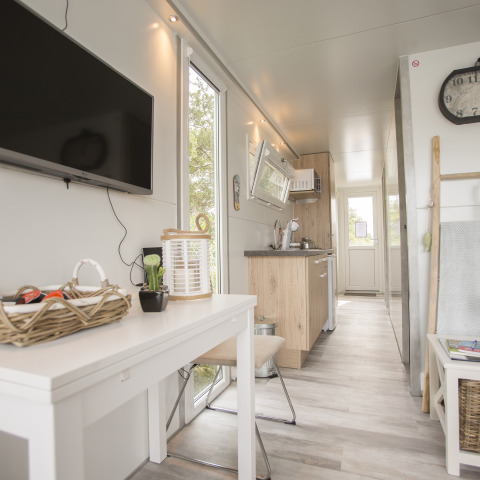 Licht, modern interieur van een woonboot aan Marina Parcs Almere met keuken, eettafel en flatscreen-tv.