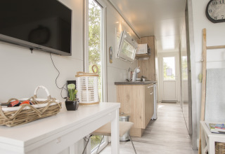 Licht, modern interieur van een woonboot aan Marina Parcs Almere met keuken, eettafel en flatscreen-tv.