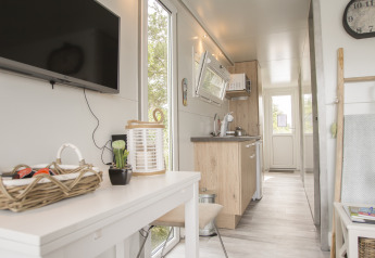 Intérieur lumineux et moderne d’une péniche à Marina Parcs Almere avec cuisine, table et télévision murale.