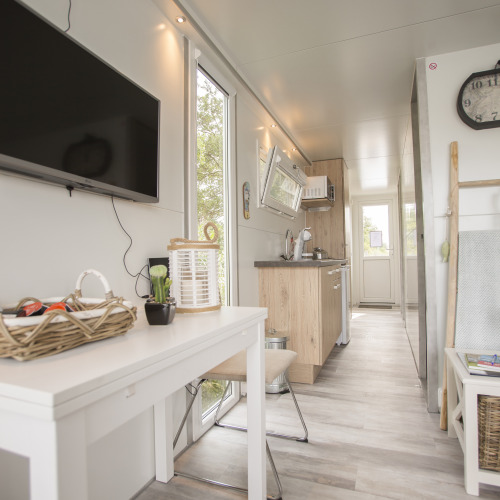 Interior luminoso y moderno de una casa flotante en Marina Parcs Almere con cocina, mesa y televisor plano.