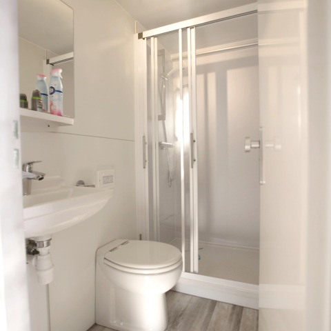 Moderne badkamer op een woonboot met wit interieur, douche, toilet en lavabo bij Marina Parcs Almere.