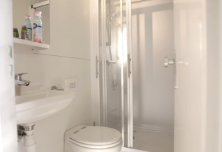Moderne badkamer op een woonboot met wit interieur, douche, toilet en wastafel bij Marina Parcs Almere.