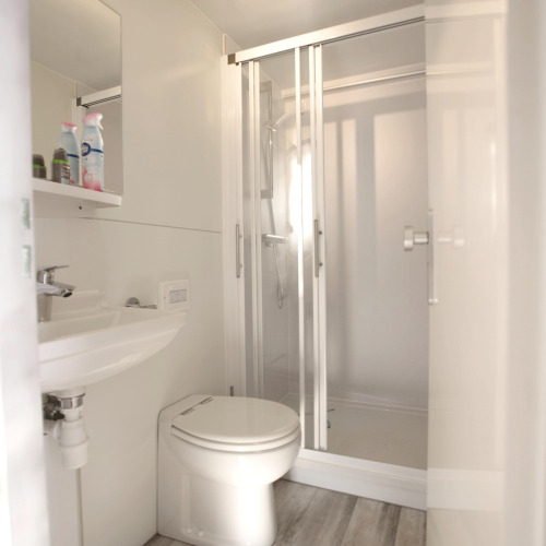 Baño moderno en una casa flotante con interior blanco, ducha, inodoro y lavabo en Marina Parcs Almere.