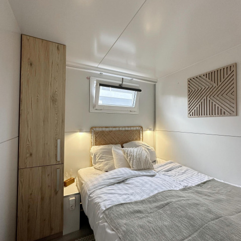 Acogedor dormitorio en una casa flotante en Almere, Países Bajos, con armario de madera y ventana.