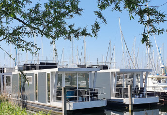 Due moderne houseboat ormeggiate al Marina Parcs Almere tra barche a vela nei Paesi Bassi.