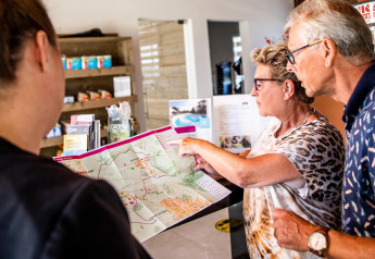 Two older visitors receive map advice at the reception of Resort Mooi Bemelen, Biebosch-tuinhuis.