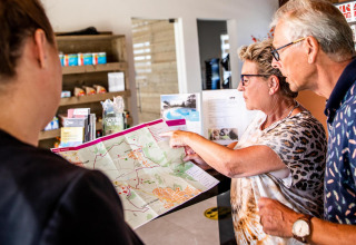 Dos visitantes mayores reciben orientación sobre un mapa en la recepción de Resort Mooi Bemelen, Biebosch-tuinhuis.