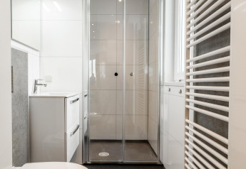 Moderne badeværelse med brusekabine, hvidt toilet og håndvask i Biebosch - tuinhuis på Resort Mooi Bemelen.