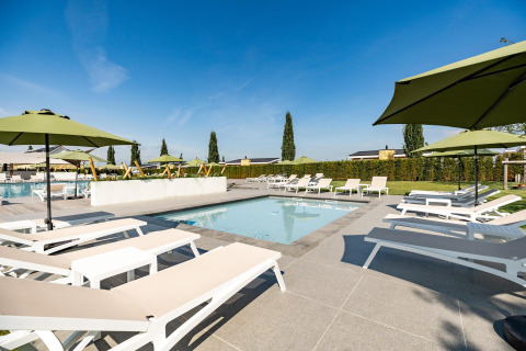 Zona de piscina exterior con tumbonas y sombrillas verdes en Resort Mooi Bemelen, Biebosch - tuinhuis, Países Bajos.
