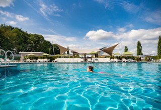 Persona nadando en la piscina exterior de Biebosch - tuinhuis en Resort Mooi Bemelen, Países Bajos, bajo el sol.