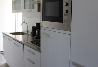 Cocina moderna con horno empotrado y cafetera en Biebosch - tuinhuis en Resort Mooi Bemelen, Países Bajos.