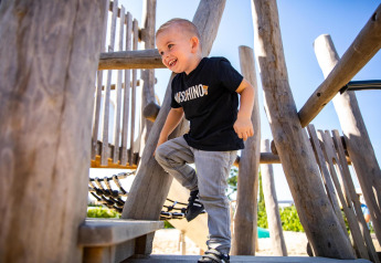 Smiling boy playing on playground at Biebosch - tuinhuis lodge, Resort Mooi Bemelen, Netherlands.