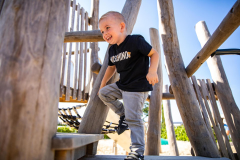 Bambino sorridente gioca nel parco giochi di Biebosch - tuinhuis, Resort Mooi Bemelen, Paesi Bassi.