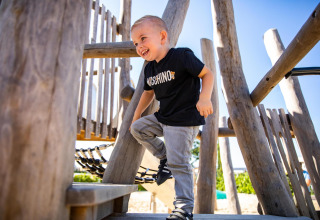 Niño sonriente jugando en el parque en Biebosch - tuinhuis, Resort Mooi Bemelen, Países Bajos.