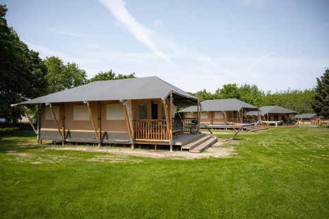 Tentes safari Villatent Cottage au Camping Borken am See en Allemagne, entourées d’herbe et d’arbres.