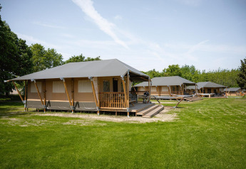 Tentes safari Villatent Cottage au Camping Borken am See en Allemagne, entourées d’herbe et d’arbres.