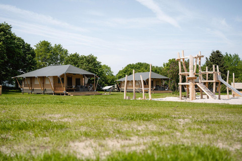 Tente safari Villatent Cottage au Camping Borken am See en Allemagne avec aire de jeux et verdure.