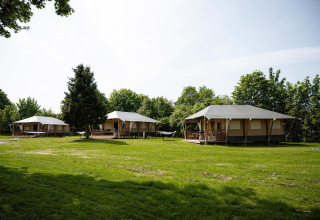 Tiendas safari Villatent Cottage en Camping Borken am See, Alemania, rodeadas de césped verde.