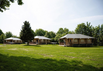 Tiendas safari Villatent Cottage en Camping Borken am See, Alemania, rodeadas de césped verde.