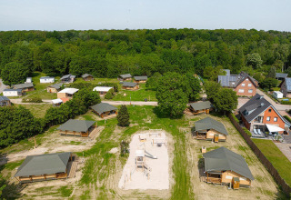 Vista aérea de tiendas safari Villatent Cottage y área de juegos en Camping Borken am See, Alemania, rodeado de naturaleza.