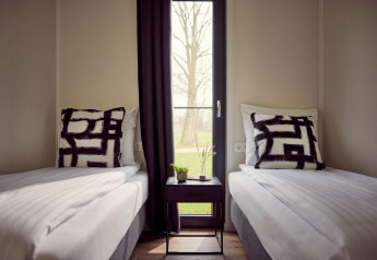 Modern bedroom with two single beds, black-white cushions and window in Holiday villa Amalia 6 lodge, Netherlands.