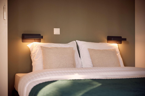 Modern tweepersoonsbed met witte kussens en gezellige verlichting in Holiday villa Amalia 6, Hofparken De Bergvennen, Nederland.