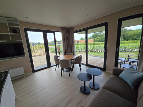 Villa vacacional moderna en Hofparken De Bergvennen, con grandes ventanales, mesa redonda y vista al jardín.
