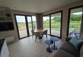 Villa vacacional moderna en Hofparken De Bergvennen, con grandes ventanales, mesa redonda y vista al jardín.