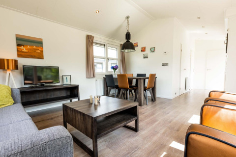 Salon moderne avec coin repas et télévision dans un chalet à EuroParcs Noordwijkse Duinen, Pays-Bas.