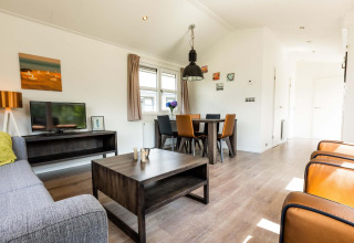 Salon moderne avec coin repas et télévision dans un chalet à EuroParcs Noordwijkse Duinen, Pays-Bas.