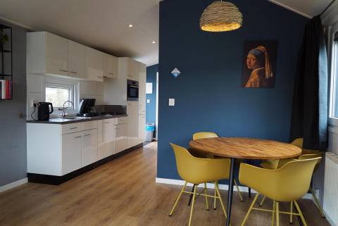 Moderne keuken en eetgedeelte met gele stoelen in Comfort cabin bij EuroParcs Noordwijkse Duinen, Nederland.