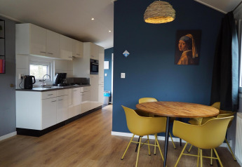 Moderne keuken en eetgedeelte met gele stoelen in Comfort cabin bij EuroParcs Noordwijkse Duinen, Nederland.