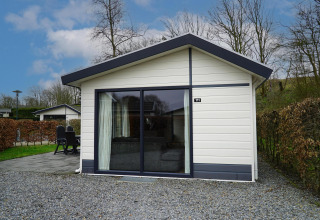Vista exterior de una cabaña Comfort con terraza en EuroParcs Noordwijkse Duinen en los Países Bajos.