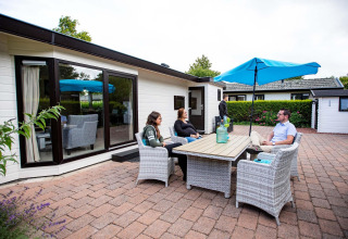 Quattro persone si rilassano all'aperto davanti a una casa vacanze a EuroParcs Noordwijkse Duinen, Paesi Bassi.
