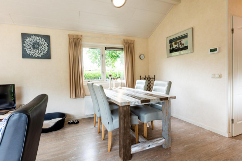 Sala da pranzo luminosa in una casa vacanze a EuroParcs Noordwijkse Duinen con tavolo rustico e quattro sedie.