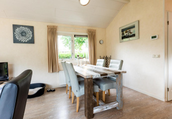 Salle à manger lumineuse dans une maison de vacances à EuroParcs Noordwijkse Duinen avec table rustique et quatre chaises.