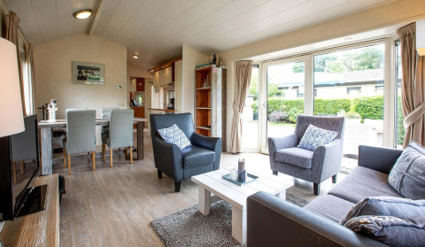 Lichte, modern ingerichte leefruimte in een vakantiehuis bij EuroParcs Noordwijkse Duinen, met grote ramen.