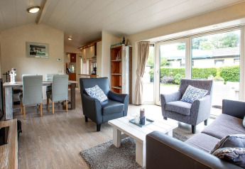Salon lumineux et moderne dans un gîte de vacances à EuroParcs Noordwijkse Duinen, Pays-Bas, avec grandes fenêtres.